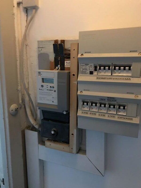 Elinstallation med gruppetavle og vekselretter til solcelleanlæg monteret på en indervæg.