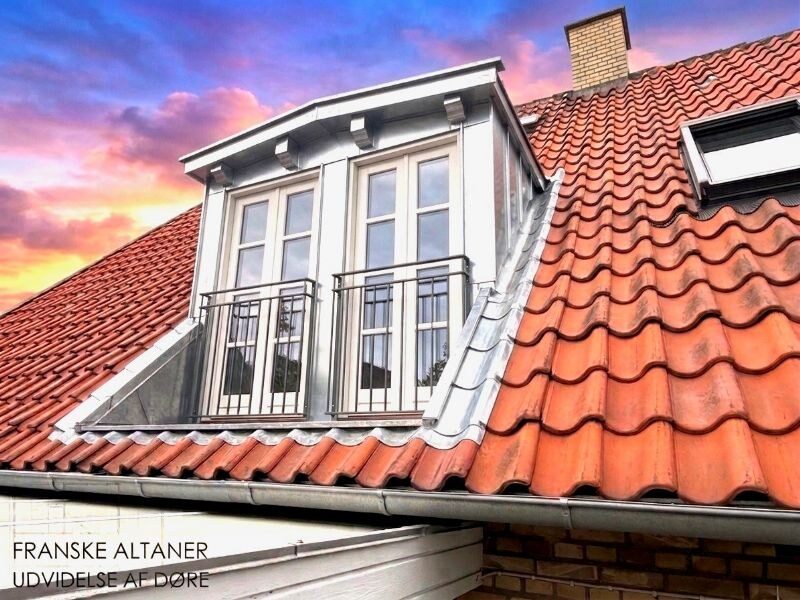 Kvist med to franske altandøre og zinkinddækning på rødt tegltag, fotograferet med dramatisk himmel.