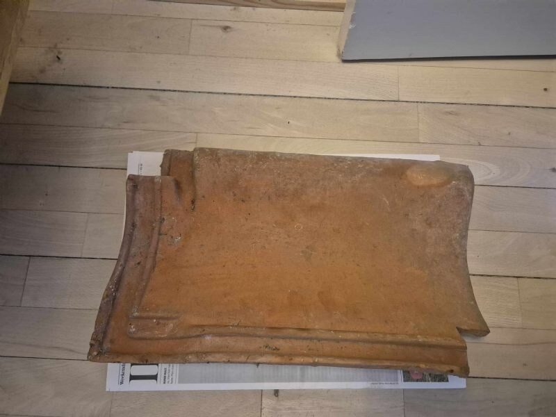 Enkelt tegltagsten fotograferet indendørs på gulv til dokumentation af type og profil.