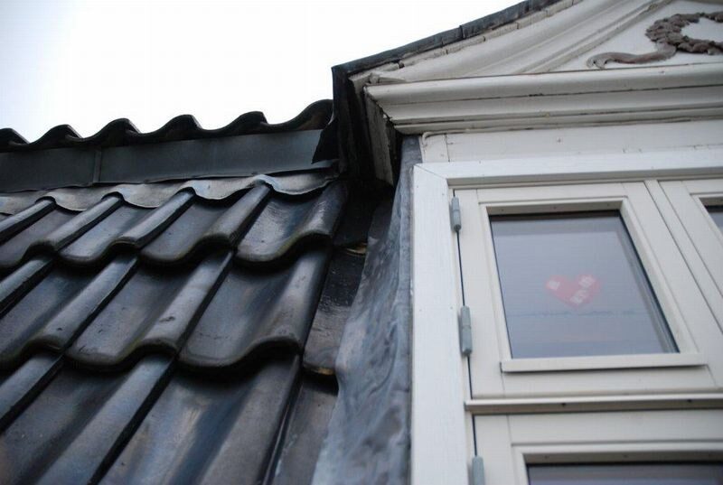 Nærbillede af en gavlkvist med sorte tagsten, zinkinddækning og hvidt vindue med et hjerte-klistermærke.