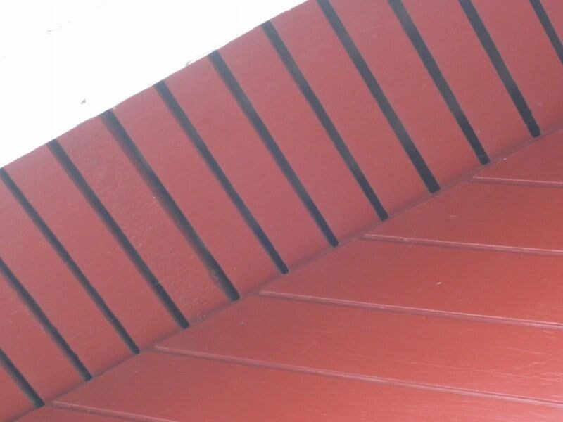 Nærbillede af rød tagbeklædning med synlig grat, sandsynligvis fibercement eller ståltag.