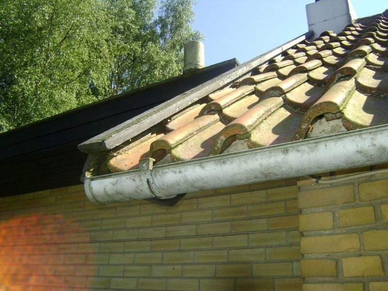 Nærbillede af gavludhæng med falstagsten, ventilationshætte og snoet tagrende med mosbegroning.