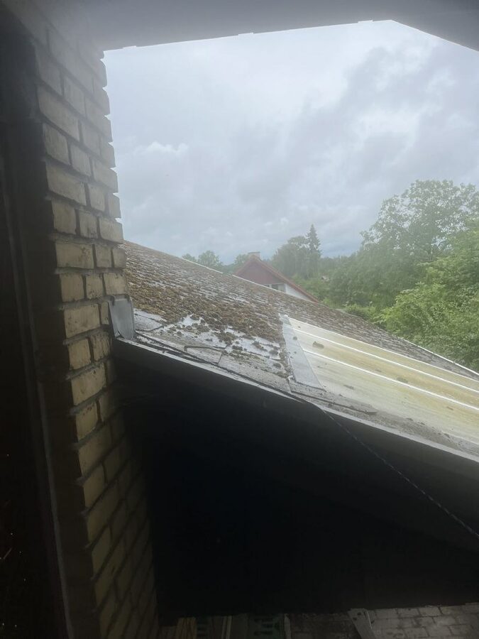 Udsigt fra en tagåbning ned over et mosbegroet eternittag med udskiftet stykke nyt tagplademateriale.
